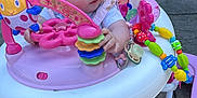 Lillian is registered to the contest to win money with this photo: baby, walker, toy, outdoor, patio, brick_wall, door, reflection, child, foot, colorful, plastic, play, person, ground, clothing, seat, activity, infant, summer