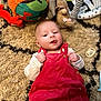 Lillian is registered to the contest to win money with this photo: baby, infant, red_overall, white_shirt, tongue_out, lying_down, rug, soft_toys, pacifier, playful, cute, child, indoors, carpet, plush_toy, colorful, smiling, face, hand, young_child