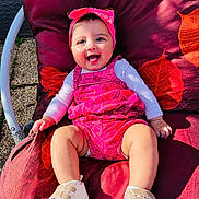 Freya a rejoint le concours — aidez-le/la à gagner de superbes lots ! baby, infant, child, smiling, portrait, headband, bow, pink_outfit, romper, white_shirt, sneakers, cushion, red_leaf_pattern, outdoor, sunlight, happy, seated, chair_frame, fabric, cute