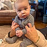 Ozzy joined the competition — help win amazing prizes! baby, infant, striped_clothing, onesie, hands, holding, curious, face, portrait, indoors, living_room, couch, carpet, person, expression, skin, head, eyes, cute, child