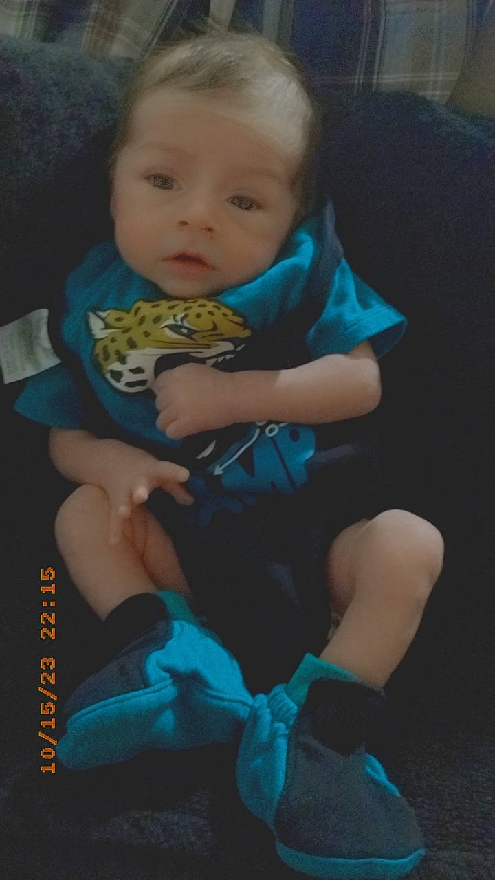 Ezekiel is registered to the contest to win money with this photo: baby, baby_products, baby_toddler_clothing, blue, cheek, child, comfort, electric_blue, eye, fun, happy, head, human_leg, knee, lap, person, sitting, sock, t_shirt, thigh