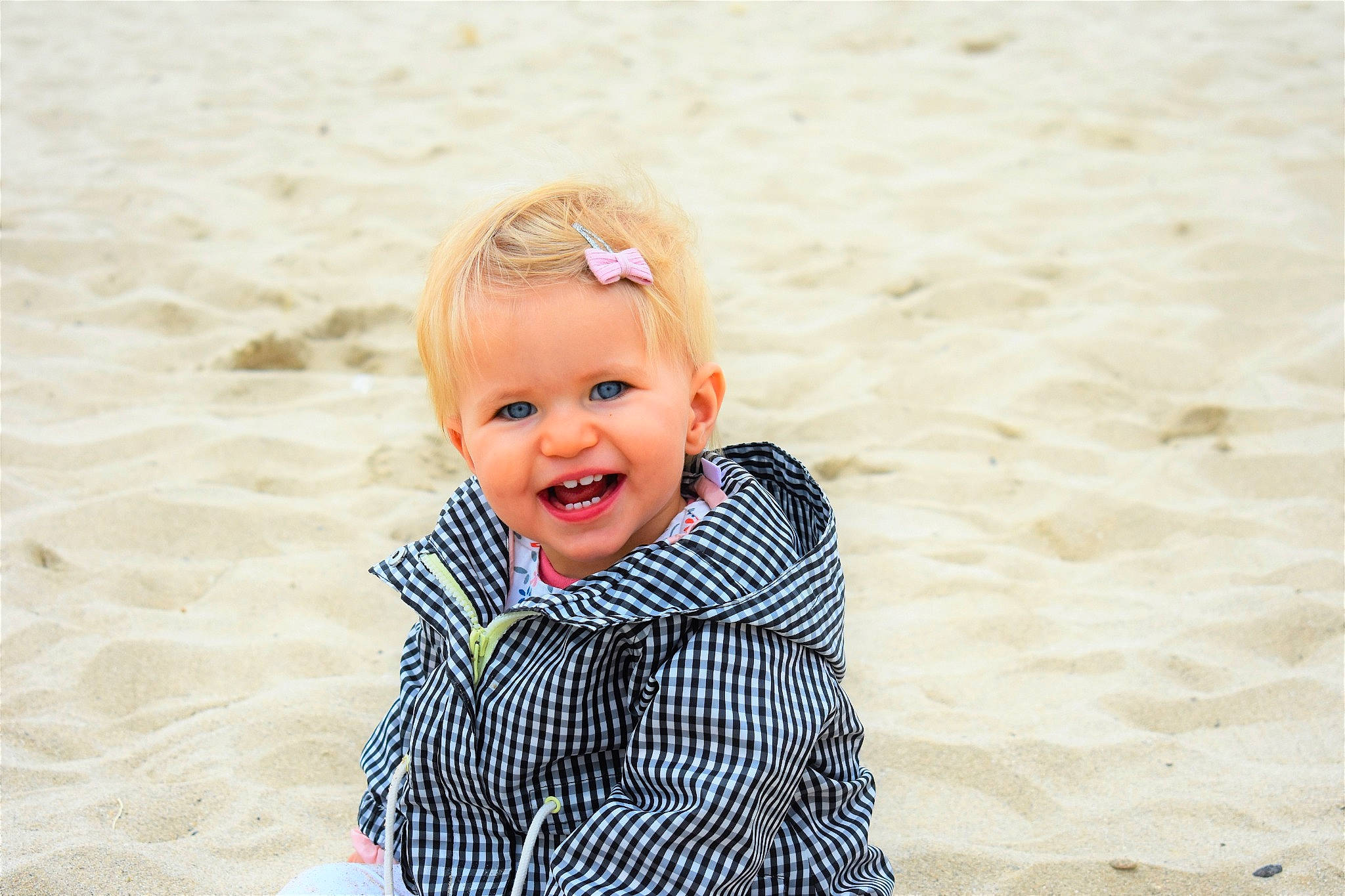 Zélie participe au concours pour gagner de l'argent avec cette photo : baby, baby_toddler_clothing, beach, child, eye, face, flooring, fun, hair, happy, head, landscape, leisure, pattern, people_in_nature, person, sand, sitting, smile, toddler