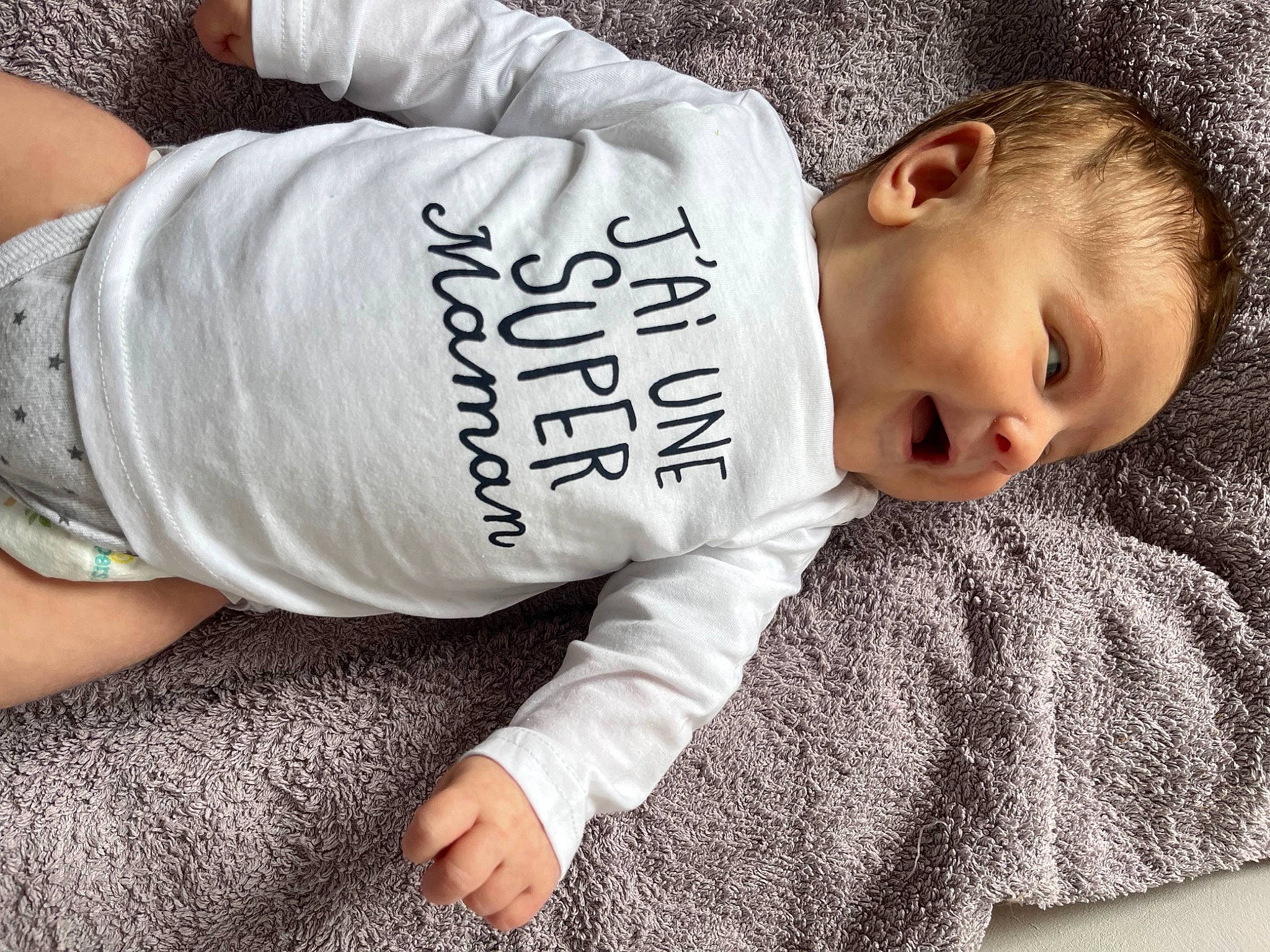 Loïs a rejoint le concours — aidez-le/la à gagner de superbes lots ! baby, baby_toddler_clothing, child, comfort, cool, elbow, flooring, fur, grass, grey, human_leg, knee, pattern, person, portrait_photography, product, sitting, sleeve, t_shirt, thigh