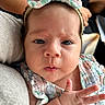 baby, infant, child, portrait, close_up, wide_eyed, headband, bow, floral, onesie, clothing, hand, fingers, cuddling, adult, arms, car_interior, seated, photography, adorable