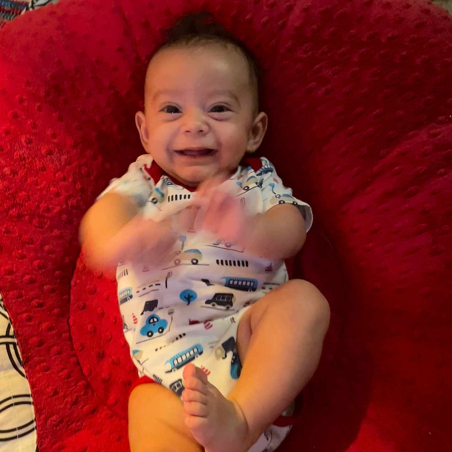 Zayden is registered to the contest to win money with this photo: baby, baby_boy, baby_girl, child, clapping, cushion, cute, face, foot, happy, indoor, infant, onesie, patterned_clothing, person, playful, red, smiling, soft, texture