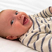 Oscar a rejoint le concours — aidez-le/la à gagner de superbes lots ! baby, smiling, striped_sweater, lying_down, white_bed, happy, child, infant, cute, face, person, cozy, eyes, mouth, skin, head, hand, portrait, indoors, baby_clothes