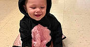 Genesis is registered to the contest to win money with this photo: baby, bat_costume, black, cabinets, carpet, child, costume, cute, ears, floor, hand_holding, happy, indoor, kneeling, person, pink, playful, smiling, tile_floor, toddler