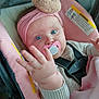 baby, infant, pacifier, headband, blue_eyes, car_seat, pink, blanket, clothing, hand, face, child, cute, straps, sweater, indoor, portrait, young, soft, cozy