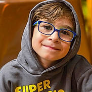 Kelyan a rejoint le concours — aidez-le/la à gagner de superbes lots ! boy, brown_background, casual_clothing, child, closeup, cute, eyewear, face, glasses, happy, hoodie, indoors, kid, portrait, sitting, smile, super_mario, warm_colors, young, youth