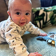Sacha a rejoint le concours — aidez-le/la à gagner de superbes lots ! baby, crawling, dinosaur_print, blanket, hand, face, smile, indoor, plush_toy, cozy, child, cute, pattern, clothing, infant, expression, person, home, soft_focus, curious