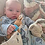 Charlie is registered to the contest to win money with this photo: baby, child, plush_toy, stuffed_animal, blanket, pajamas, couch, soft_fabric, comfort, indoor, cute, infant, face, hand, sleepy, cozy, relaxing, toy, childhood, home