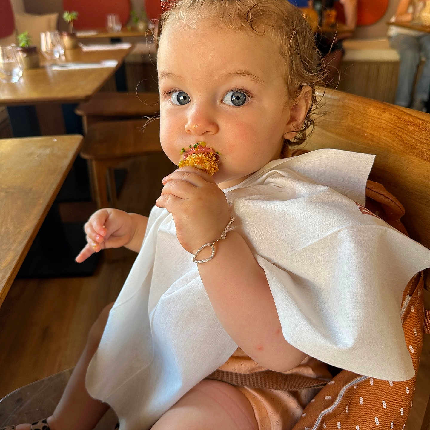 Lyccica a rejoint le concours — aidez-le/la à gagner de superbes lots ! background_people, bib, blue_eyes, bracelet, child, curly_hair, cute, dining, eating, face, food, high_chair, indoor, leopard_print_shoes, messy_fingers, person, restaurant, seat, toddler, wooden_table