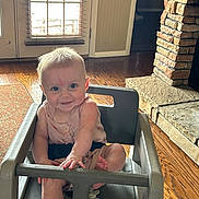 Lily joined the competition — help win amazing prizes! baby, child, clothing, door, face, foot, furniture, hand, happy, high_chair, indoor, infant, light, person, room, seat, smiling, stone_fireplace, window_blinds, wooden_floor