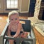 baby, child, high_chair, smiling, indoor, wooden_floor, stone_fireplace, door, window_blinds, light, person, infant, furniture, happy, face, hand, foot, seat, clothing, room