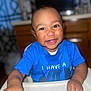 baby, blue_shirt, child, clothing, cute, expression, face, hand, happy, high_chair, indoor, infant, kitchen, person, portrait, skin, smiling, table, teeth, young_child