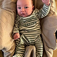 Léon a rejoint le concours — aidez-le/la à gagner de superbes lots ! baby, infant, striped_pajamas, raised_fist, blanket, cozy, smiling, person, child, cute, indoors, soft_texture, portrait, sleepwear, newborn, happy, face, small_hands, lying_down, comfortable