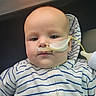 Sawyer is registered to the contest to win money with this photo: baby, infant, child, face, portrait, sitting, striped_onesie, clothing, medical_tube, feeding_tube, car_interior, vehicle, seat, head, eyes, nose, mouth, indoor, close_up, photography