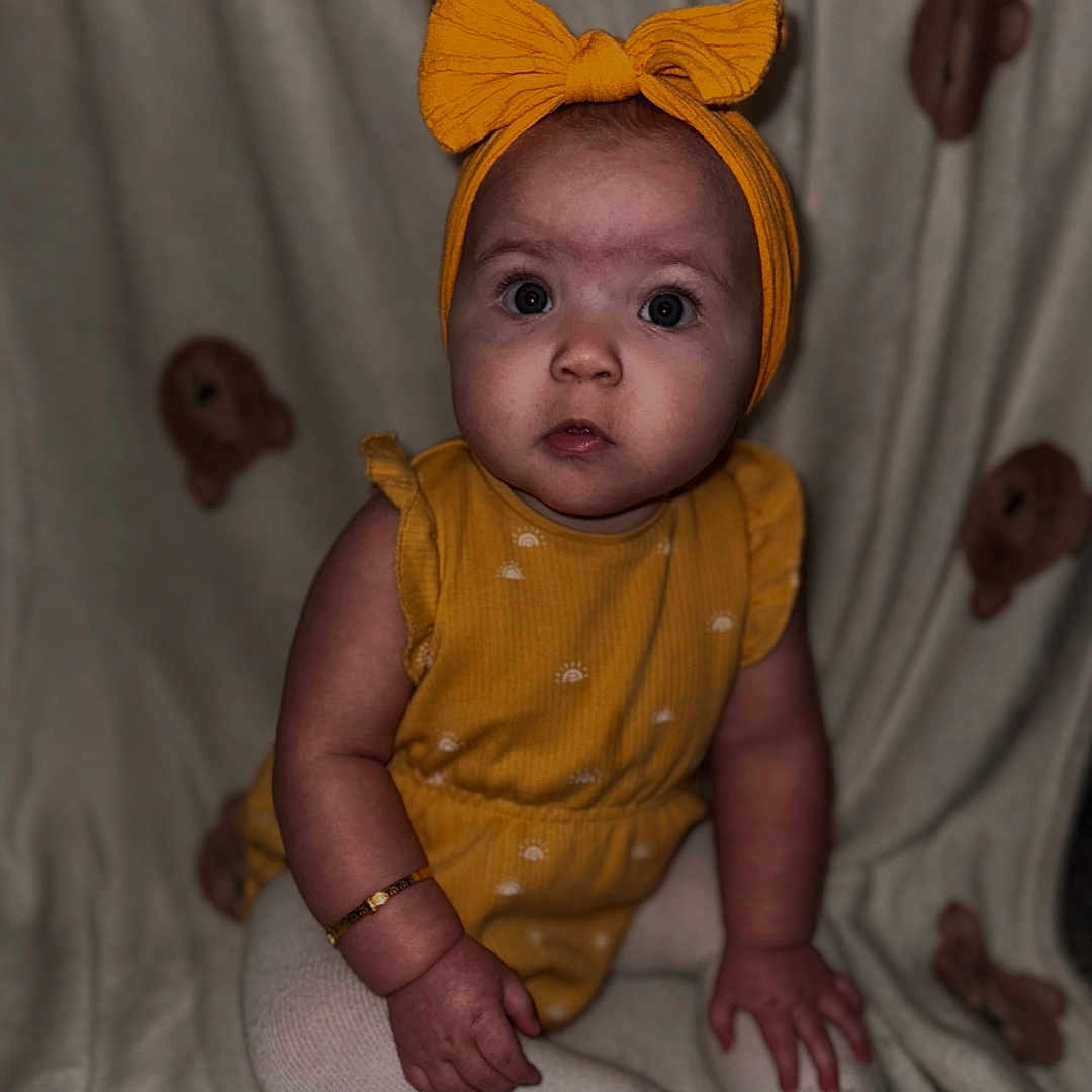 Alayah-Ray is registered to the contest to win money with this photo: baby, blanket, bracelet, child, chubby_cheeks, closeup, curious, cute, expression, headband, indoors, infant, person, portrait, sitting, small_hands, soft_lighting, teddy_bear_pattern, white_tights, yellow_outfit