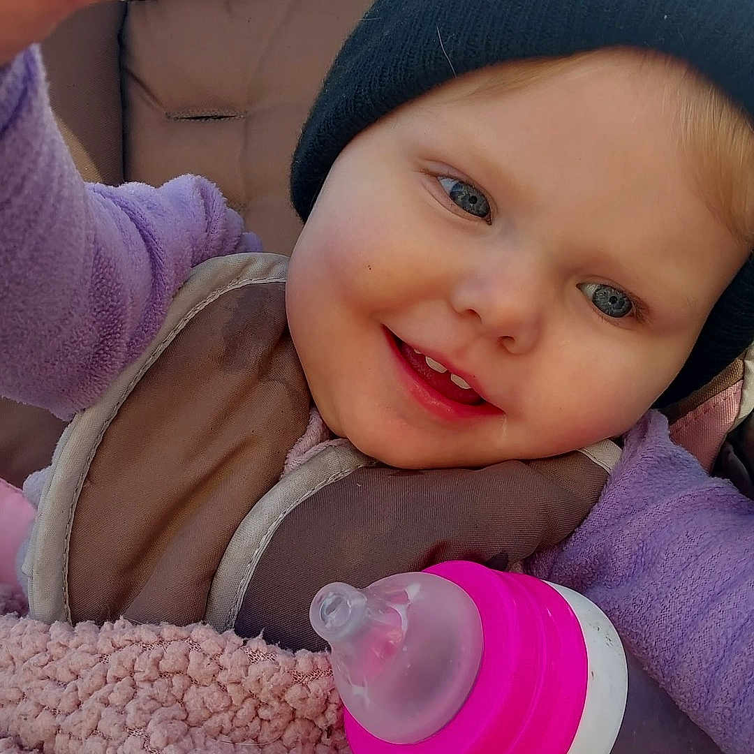 Elizabeth is registered to the contest to win money with this photo: baby, beanie, blanket, blue_eyes, bottle, child, cozy, cute, face, hand, happy, infant, outdoor, portrait, purple_clothing, sippy_cup, smiling, stroller, toddler, warm_clothing