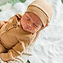 baby, newborn, infant, sleeping, hat, knit_hat, beige_clothing, onesie, hand, adult_hand, blanket, bedding, cozy, portrait, closeup, soft_light, buttons, fabric, resting, nursery