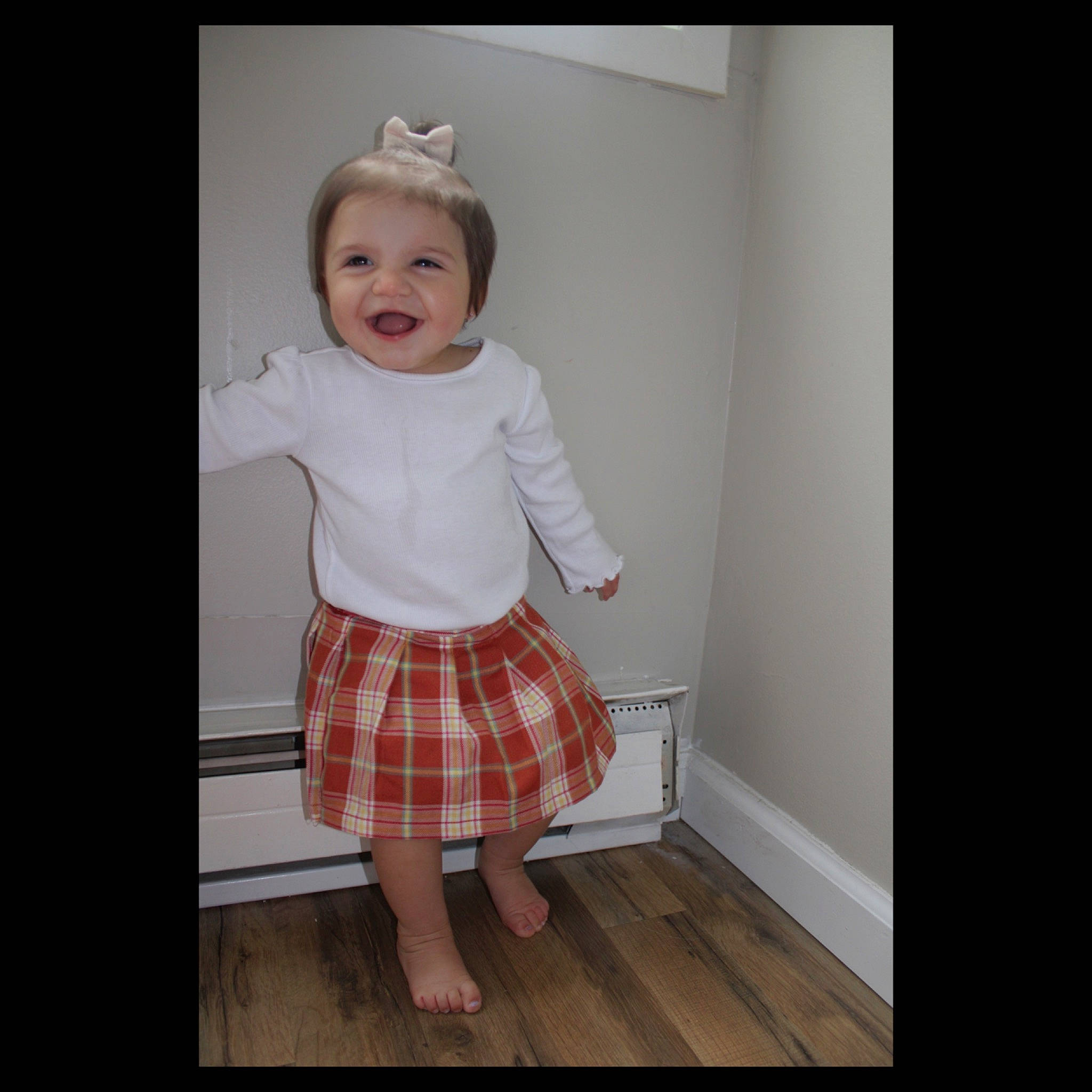 Eliana joined the competition — help win amazing prizes! baby, baby_toddler_clothing, child, flooring, happy, hardwood, human_leg, knee, outerwear, pattern, person, plaid, product, room, sleeve, smile, tartan, toddler, uniform, waist
