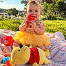 Anastasia is registered to the contest to win money with this photo: baby, child, tutu_dress, headband, yellow_clothing, smiling, outdoor, grass, blanket, toy, red_toy, plush_toy, winnie_the_pooh, sunlight, greenery, happy, sitting, cute, portrait, playtime