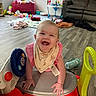 baby, smiling, toy_car, indoor, living_room, floor, playtime, child, happy, clothing, bib, furniture, couch, window, light, plastic_toy, flooring, blanket, sippy_cup, play_area