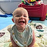 Anastasia joined the competition — help win amazing prizes! baby, smiling, child, indoor, bib, yellow_pants, toy_box, quilt, window_blinds, happy, sitting, cute, infant, play_area, colorful, face, person, head, expression, clothing