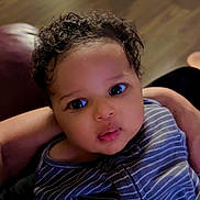 Adonai is registered to the contest to win money with this photo: baby, child, cozy, curly_hair, cute, expression, face, floor, holding, home, indoor, infant, looking_up, person, portrait, skin, soft_light, striped_clothing, wooden_floor, young_child