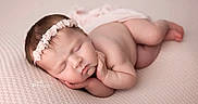 Ashlyn is registered to the contest to win money with this photo: newborn, baby, sleeping, infant, portrait, headband, floral_headband, blanket, knitted_blanket, pink, peaceful, curled_up, lying_down, indoors, soft_lighting, photography, closeup, face, bare_skin, relaxed