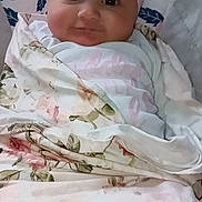 Liliana is registered to the contest to win money with this photo: baby, infant, bow, headwrap, swaddle, blanket, floral_pattern, pink, cheeks, eyes, smile, portrait, closeup, indoor, fabric, cute, newborn, cushion, head, adorable