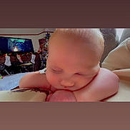 Danielle is registered to the contest to win money with this photo: baby, sleeping, face, arm, christmas_tree, stockings, television, holiday, indoor, cozy, child, resting, blanket, couch, furniture, person, home, decor, relaxing, cute