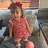 Kristabelle joined the competition — help win amazing prizes! toddler, child, girl, red_bow, checkered_clothing, couch, pillows, pink_piggy_bank, books, indoors, window_blinds, smiling, standing, socks, shoes, playroom, home, furniture, happy, cute