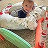 baby, infant, child, smiling, face, portrait, lying_down, play_mat, pillows, blanket, striped_clothing, long_sleeves, indoor, living_room, carpet, toy, play_gym, colorful, home, happy