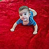 baby, child, infant, portrait, lying_down, red_blanket, blue_shirt, smiling, curious, face, eyes, arms, hands, feet, indoor, close_up, crawling, soft_blanket, adorable, photography