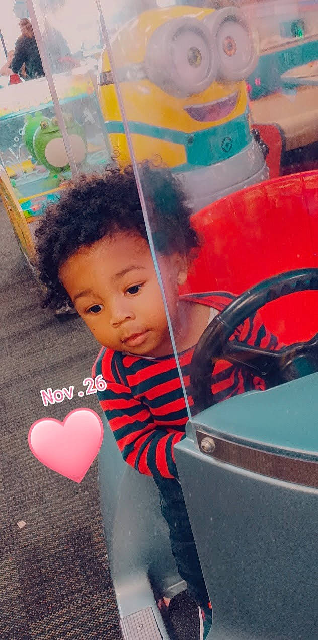 Ty'Destined is registered to the contest to win money with this photo: automotive_exterior, automotive_tire, baby, black_hair, bumper, child, cool, facial_expression, flooring, fun, hairstyle, happy, hood, leisure, motor_vehicle, person, skin, t_shirt, toddler, vehicle_door