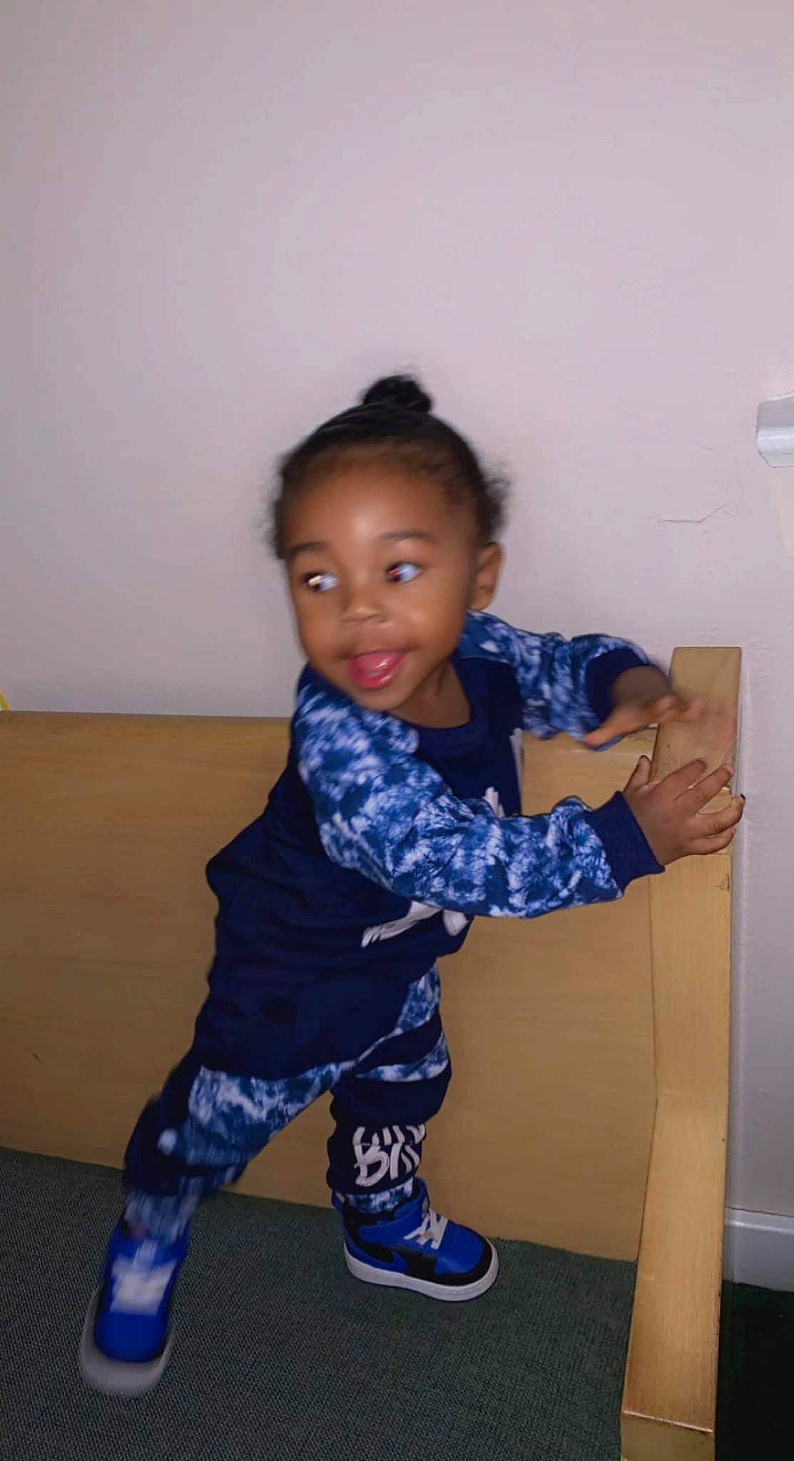 Ty'Destined is registered to the contest to win money with this photo: baby_toddler_clothing, child, elbow, electric_blue, flooring, foot, fun, human_leg, knee, pattern, person, room, sandal, shoulder, sitting, sleeve, smile, sock, t_shirt, thigh