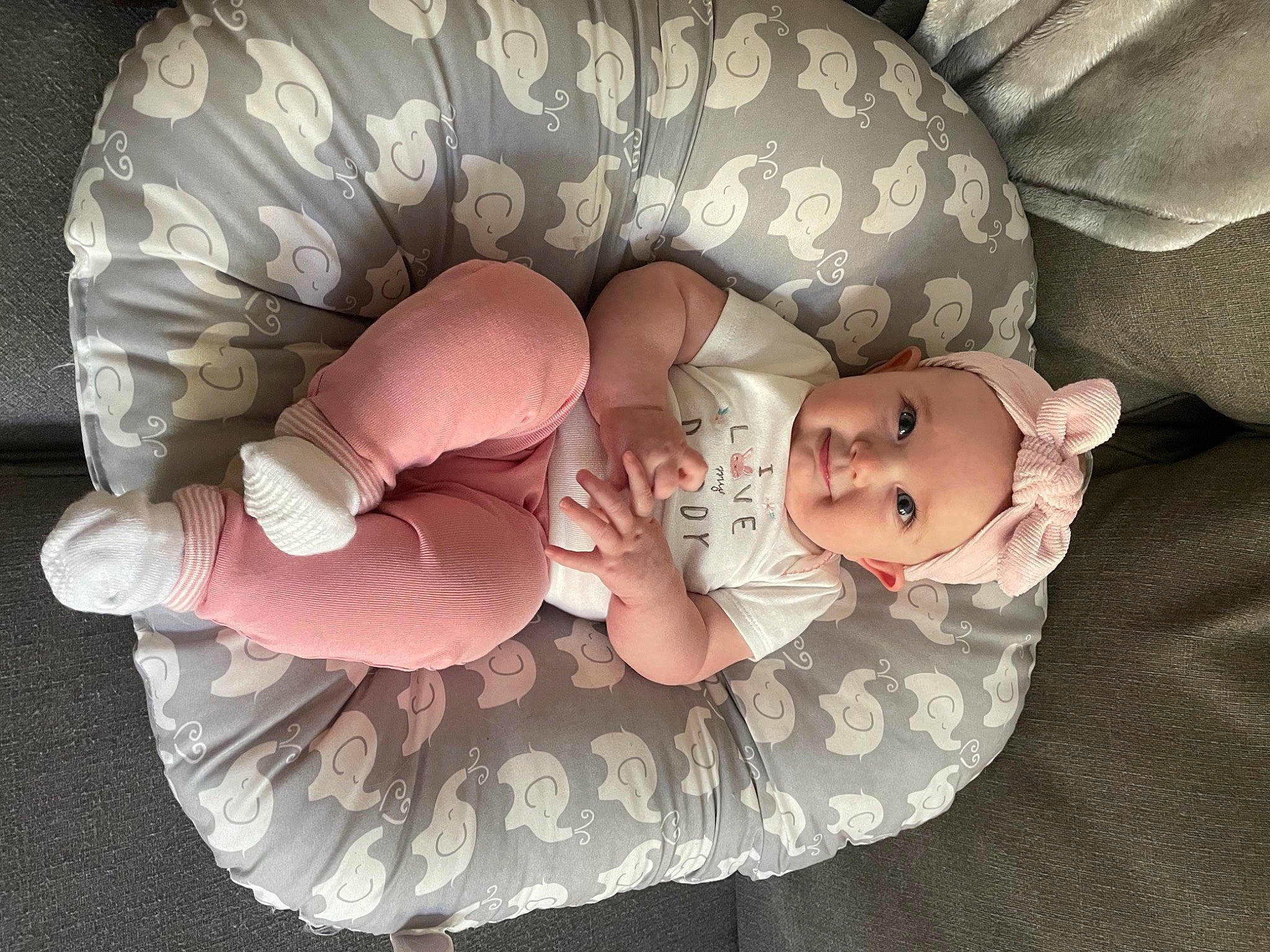 Sydney is registered to the contest to win money with this photo: baby, baby_products, baby_sleeping, baby_toddler_clothing, child, comfort, fashion_accessory, finger, foot, headgear, headwear, human_body, lap, nail, person, product, sitting, skin, sleeve, textile