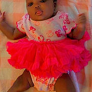 Jahlani is registered to the contest to win money with this photo: baby, infant, child, portrait, lying_down, blanket, pink, tutu, dress, flower_headband, headband, smiling, tongue_out, dark_skin, indoor, cute, fashion, bedding, full_body, photography