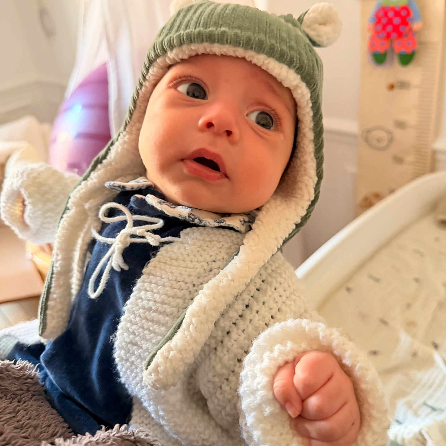 Angel a rejoint le concours — aidez-le/la à gagner de superbes lots ! baby, blanket, child, clown_toy, cozy, curious, cute, ear_flap_hat, expression, face, furniture, growth_chart, hand, hat, indoor, infant, knitted_jacket, portrait, soft_lighting, warm_clothing