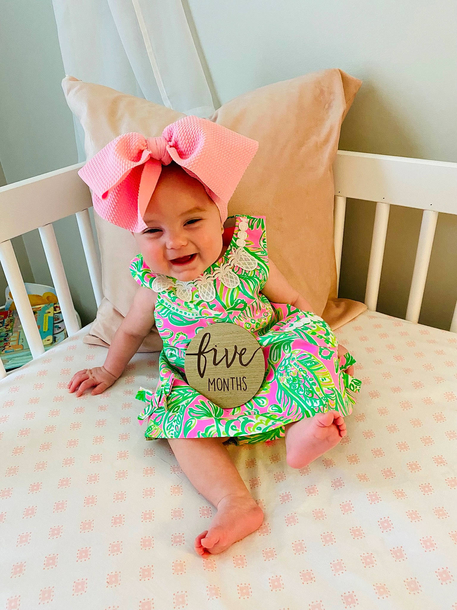 Emersyn is registered to the contest to win money with this photo: baby, baby_toddler_clothing, child, comfort, dress, flooring, foot, happy, headwear, human_leg, joy, knee, linens, magenta, pattern, person, pink, skin, sleeve, sock
