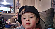 Cody joined the competition — help win amazing prizes! toddler, child, cap, red_sweater, couch, living_room, tattooed_adult, bowl, home_decor, picture_frame, clock, casual, indoor, person, furniture, relaxed, hat, jeans, toy, family