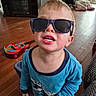 Cody joined the competition — help win amazing prizes! toddler, child, sunglasses, blue_pajamas, dinosaur_print, wooden_floor, toy_guitar, indoor, smiling, face, person, home, playful, barefoot, young_child, furniture, cozy, casual, cute, portrait