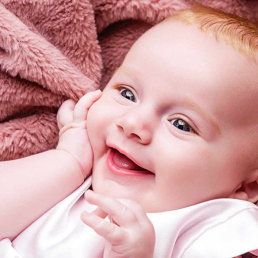 Isabella is registered to the contest to win money with this photo: baby, blanket, child, closeup, comfort, cuddle, cute, expression, face, hand, happy, infant, joy, newborn, pink, portrait, skin, smiling, soft, warm