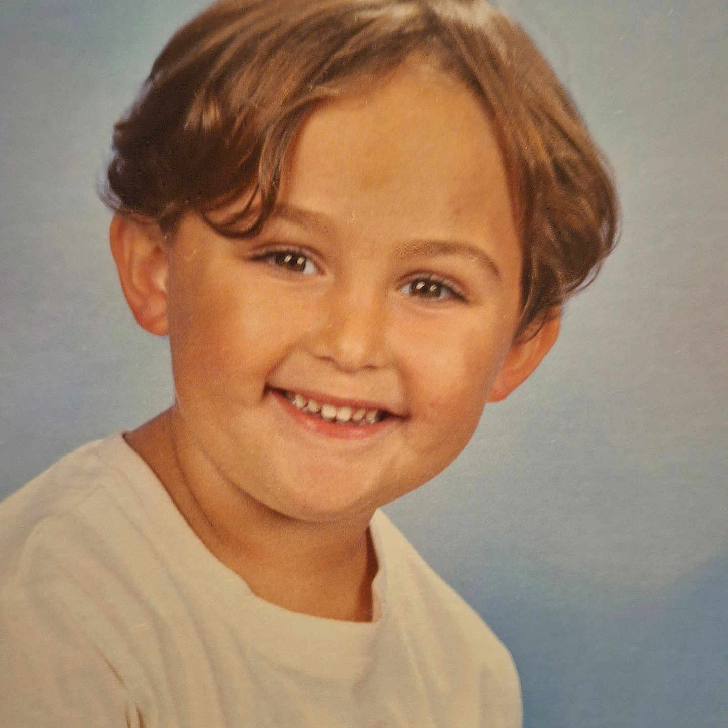 Aylan a rejoint le concours — aidez-le/la à gagner de superbes lots ! blue_background, brown_hair, casual_clothing, child, childhood, cute, face, happy, headshot, indoors, kid, logo, person, photography, portrait, school_photo, smiling, studio, tshirt, young