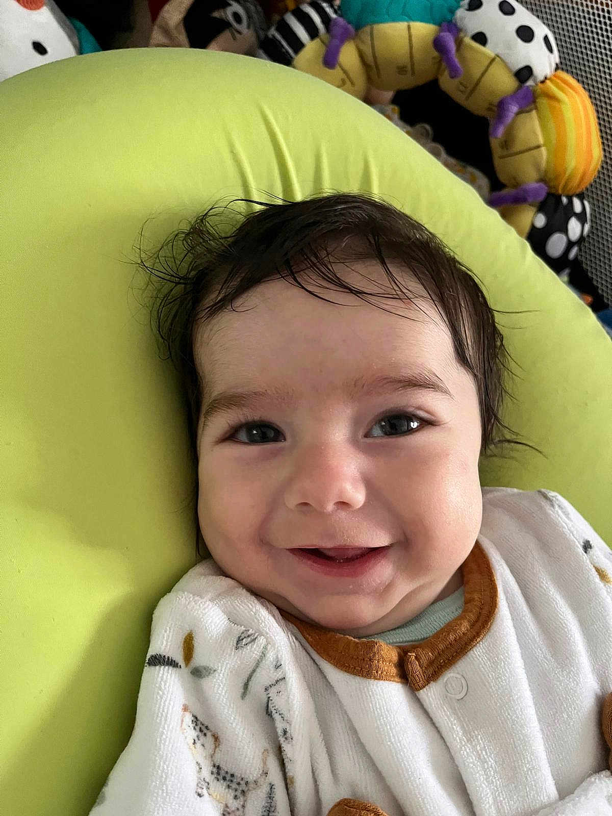 Matthieu participe au concours pour gagner de l'argent avec cette photo : baby, smile, face, infant, child, cushion, green, clothing, toy, happy, indoors, portrait, cozy, cute, young, sitting, head, eyes, skin, expression