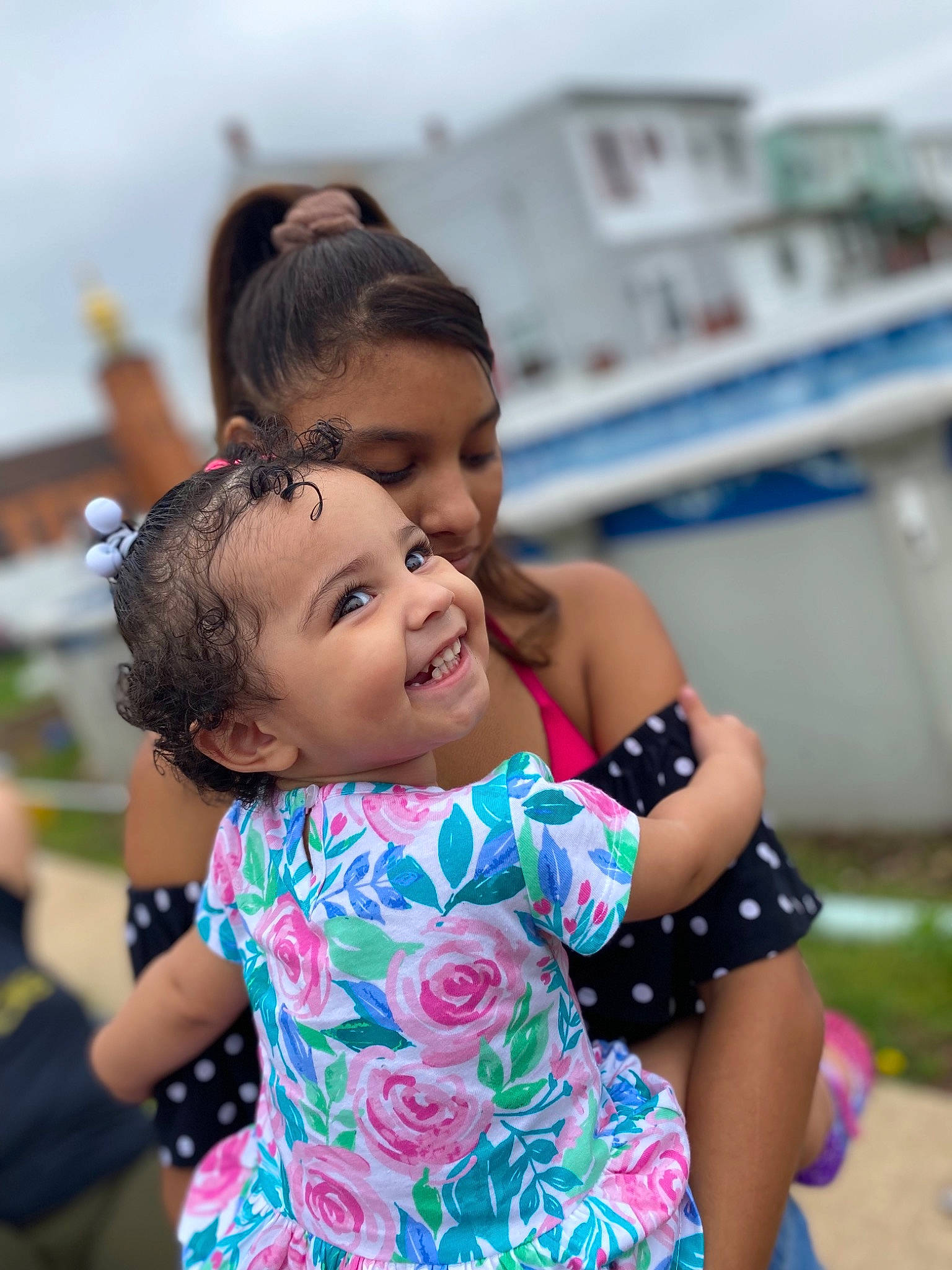 Delilah is registered to the contest to win money with this photo: ceremony, child, event, friendship, fun, gesture, grass, hairstyle, happy, hug, joy, leisure, person, photograph, recreation, smile, t_shirt, toddler, tourism, tradition