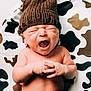 baby, newborn, yawning, knitted_hat, brown_hat, infant, cute, cow_print, blanket, clothing, soft_texture, hands, portrait, sleepy, cozy, child, lying_down, skin, expression, adorable