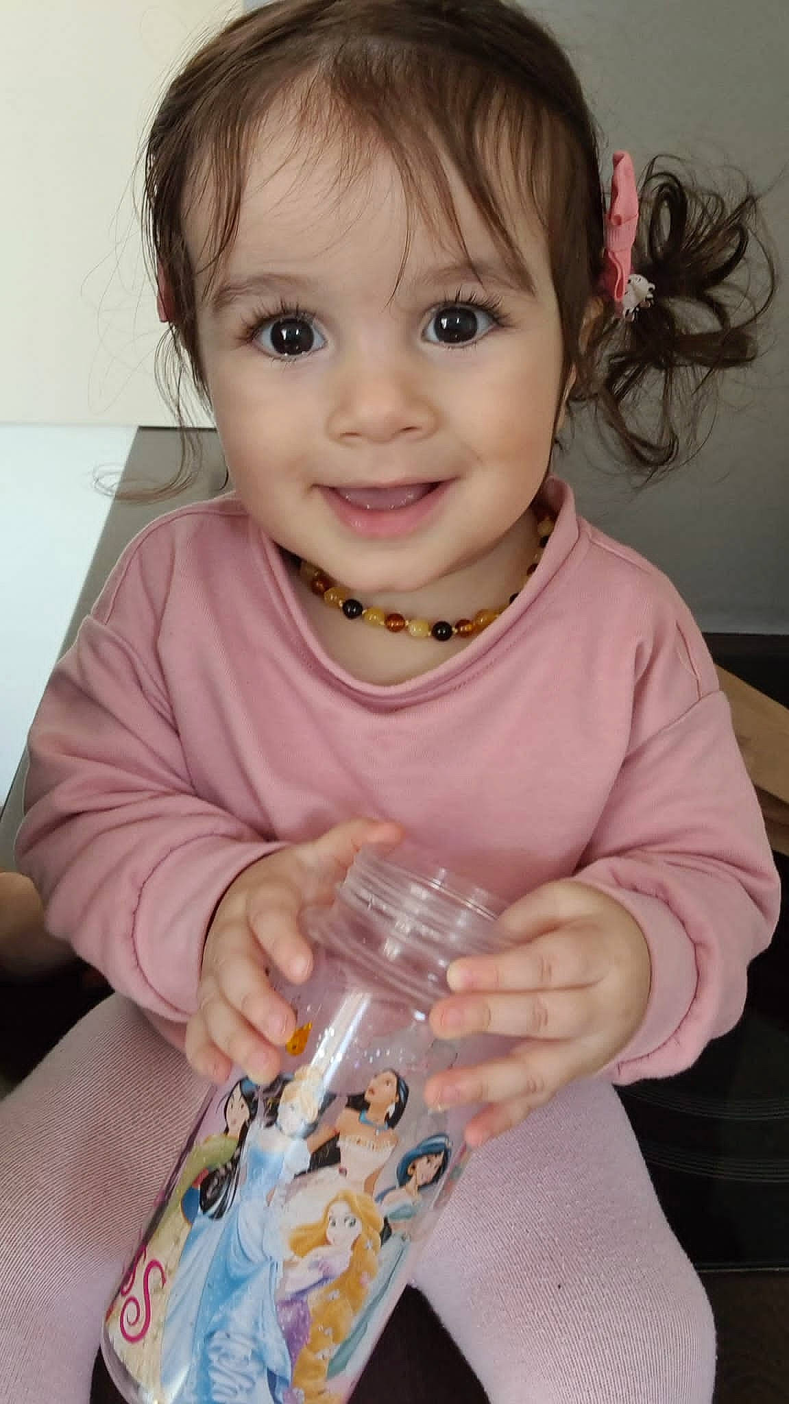 Lara participe au concours pour gagner de l'argent avec cette photo : baby_toddler_clothing, cheek, child, dress, drinkware, eyelash, finger, hair, hand, happy, iris, joy, nose, organ, person, pink, plastic_bottle, skin, sleeve, smile