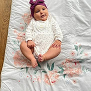 Lucie participe au concours pour gagner de l'argent avec cette photo : baby, infant, headband, purple, bow, blanket, floral_pattern, wooden_floor, white_clothing, cute, child, lying_down, soft_lighting, indoors, small_hands, small_feet, portrait, adorable, calm, looking_at_camera